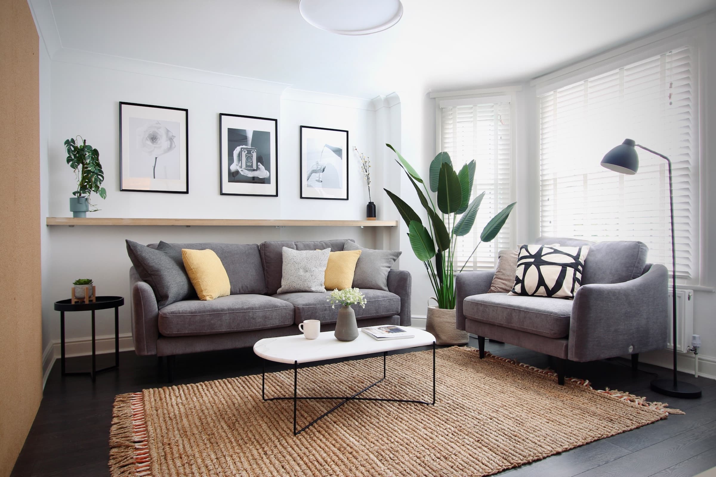 The living room — two grey sofas around a coffee table, gallery wall and shuttered windows
