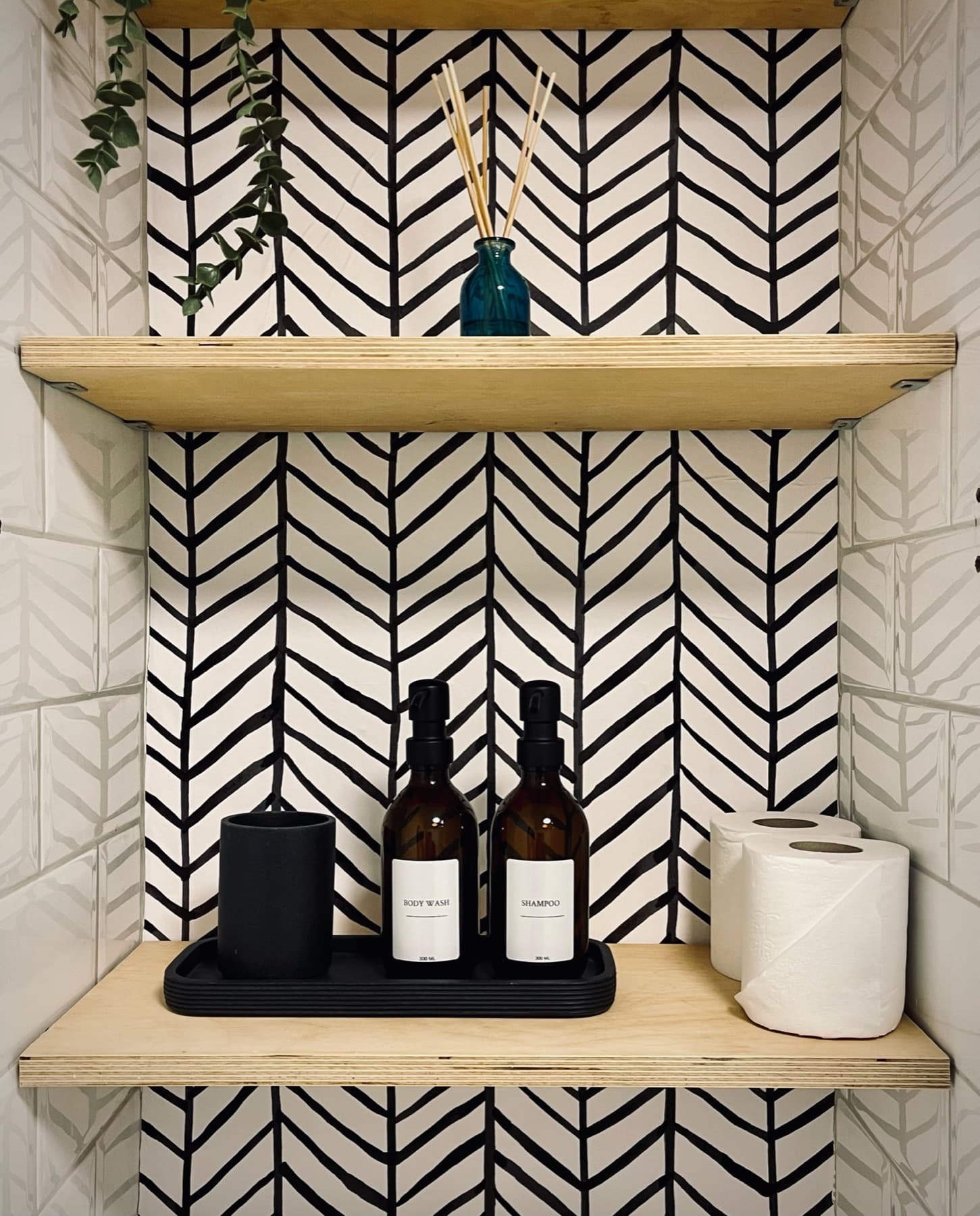 Toiletries on wooden shelves set into herringbone tiling